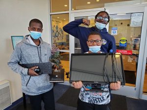 Three children holding a computer while cheering.