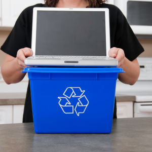 Person holding open laptop next to a recycling box.