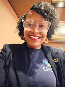 Smiling Canopy Children’s Solutions staff member wearing clear-framed glasses, a navy blazer, and a Canopy shirt.