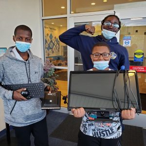 Three children holding a computer while cheering.