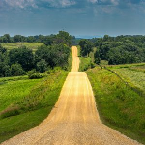 A long shot of a country road with grass fields on either side.